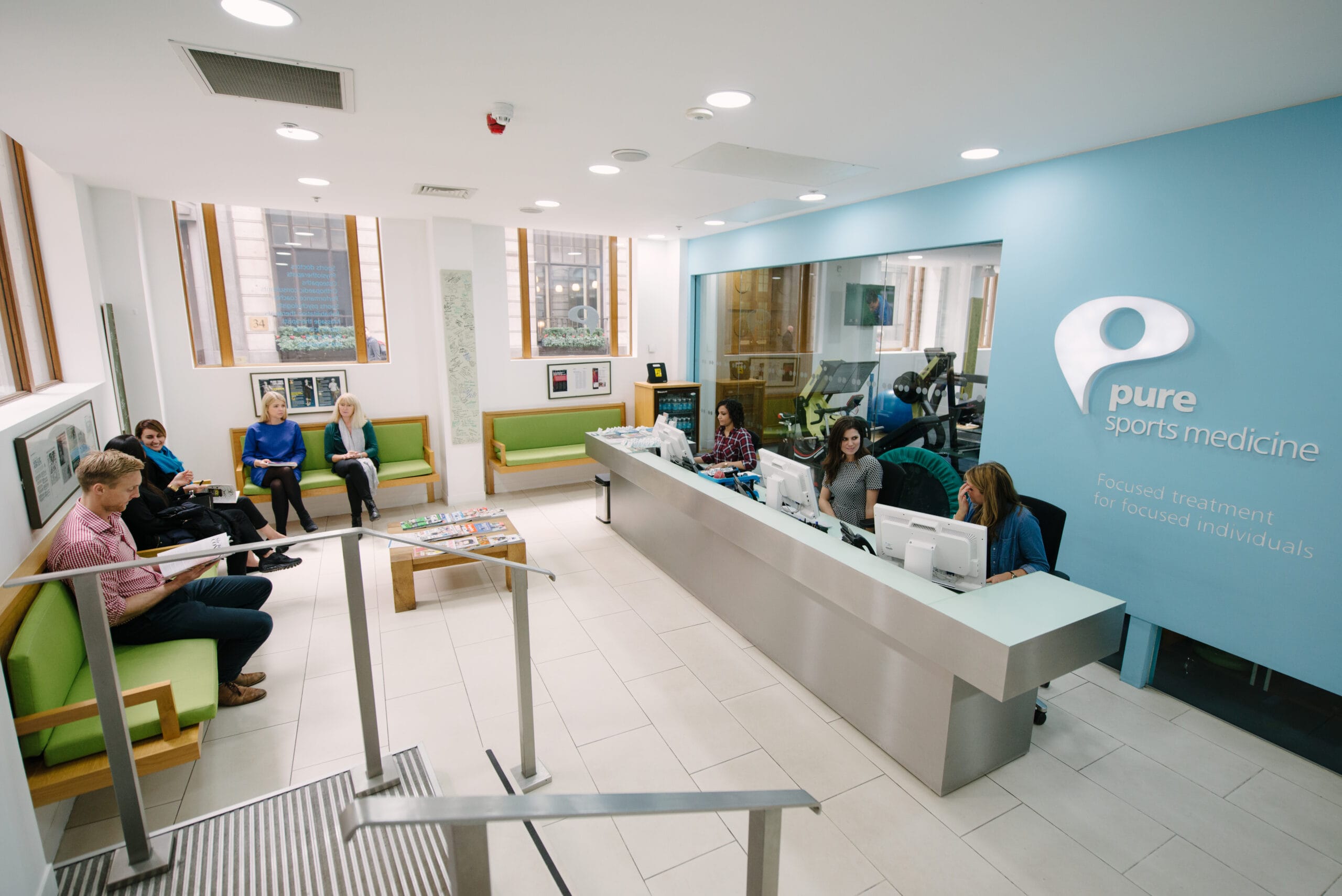 Pure Sports Medicine Raynes Park Wimbledon waiting room and reception with 3 receptionists and patients waiting