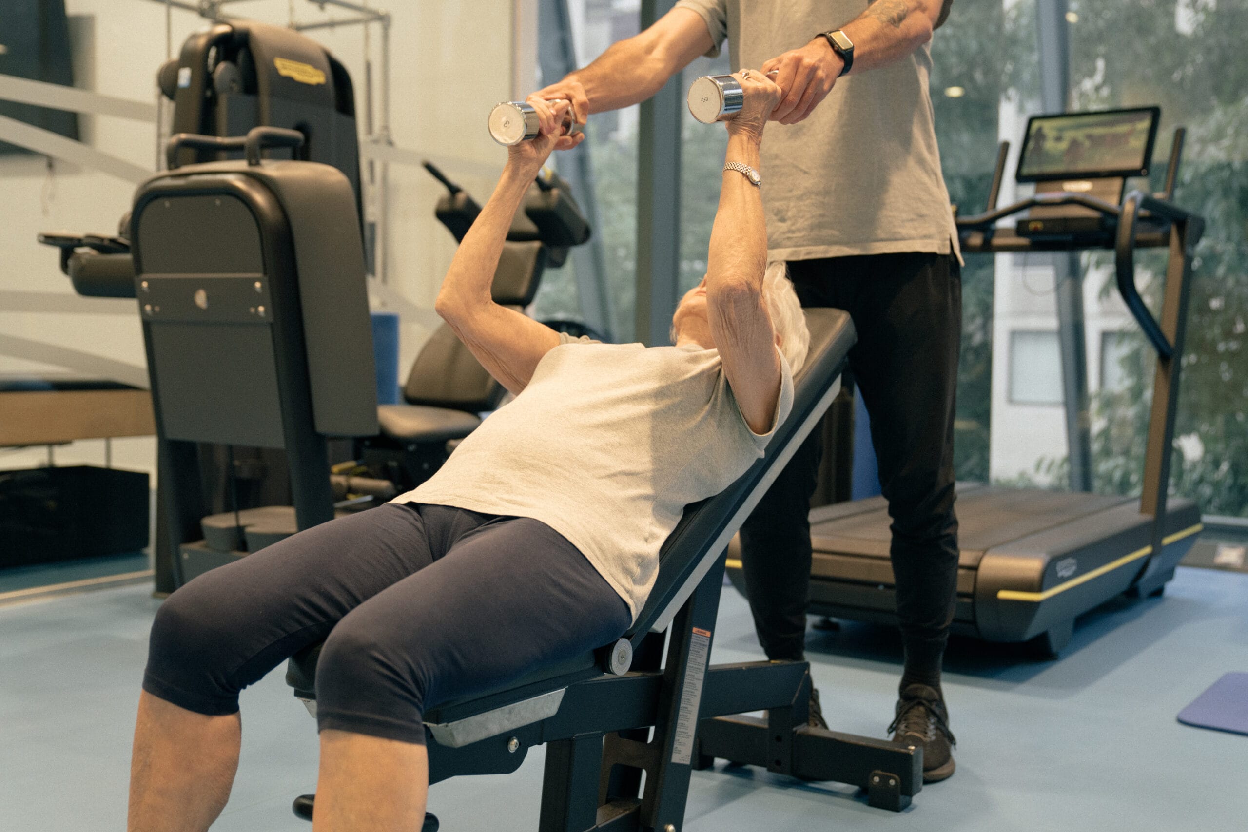 older woman with weights laying on bench