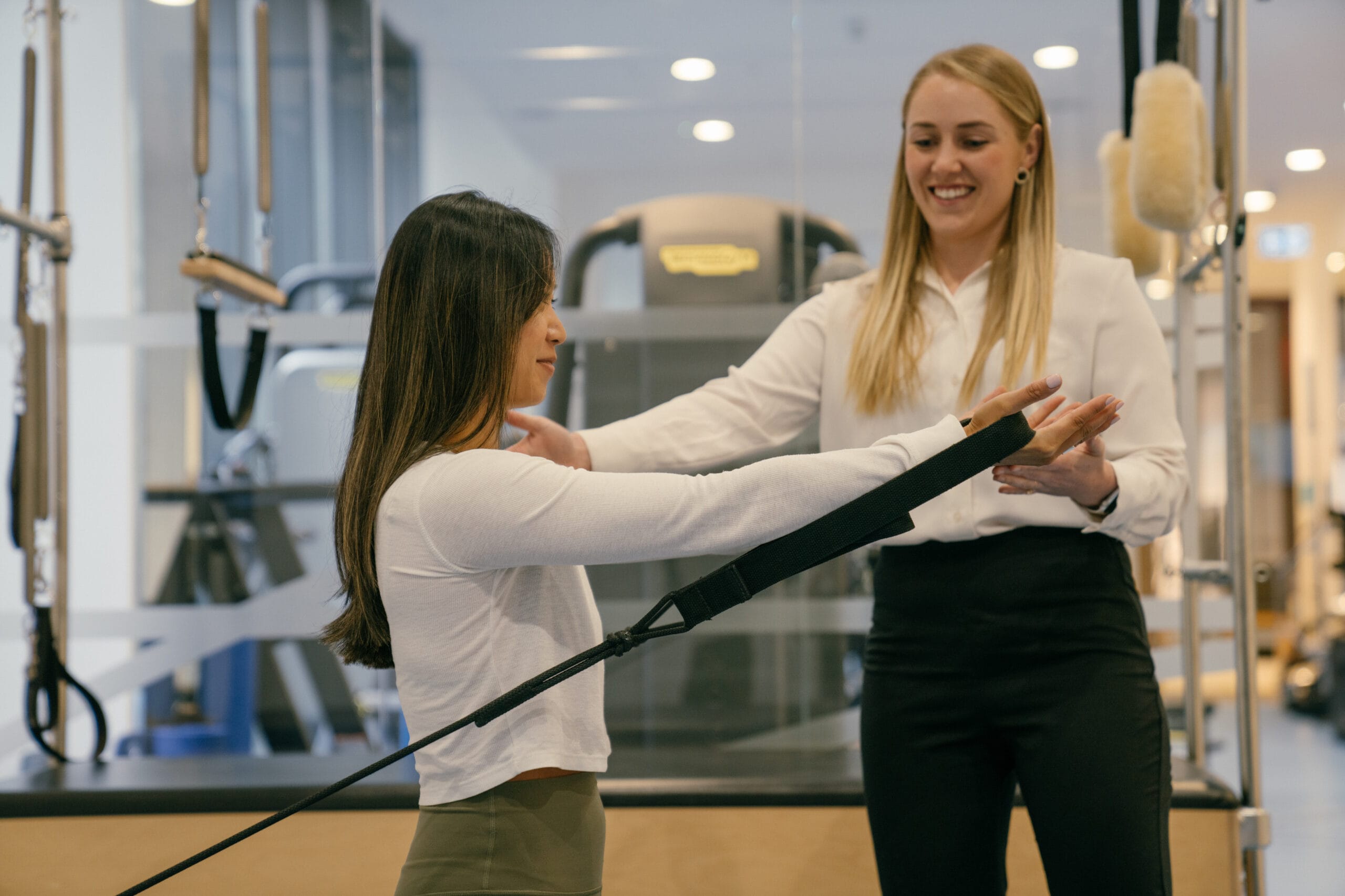 clinician supporting woman in Pilates exercise