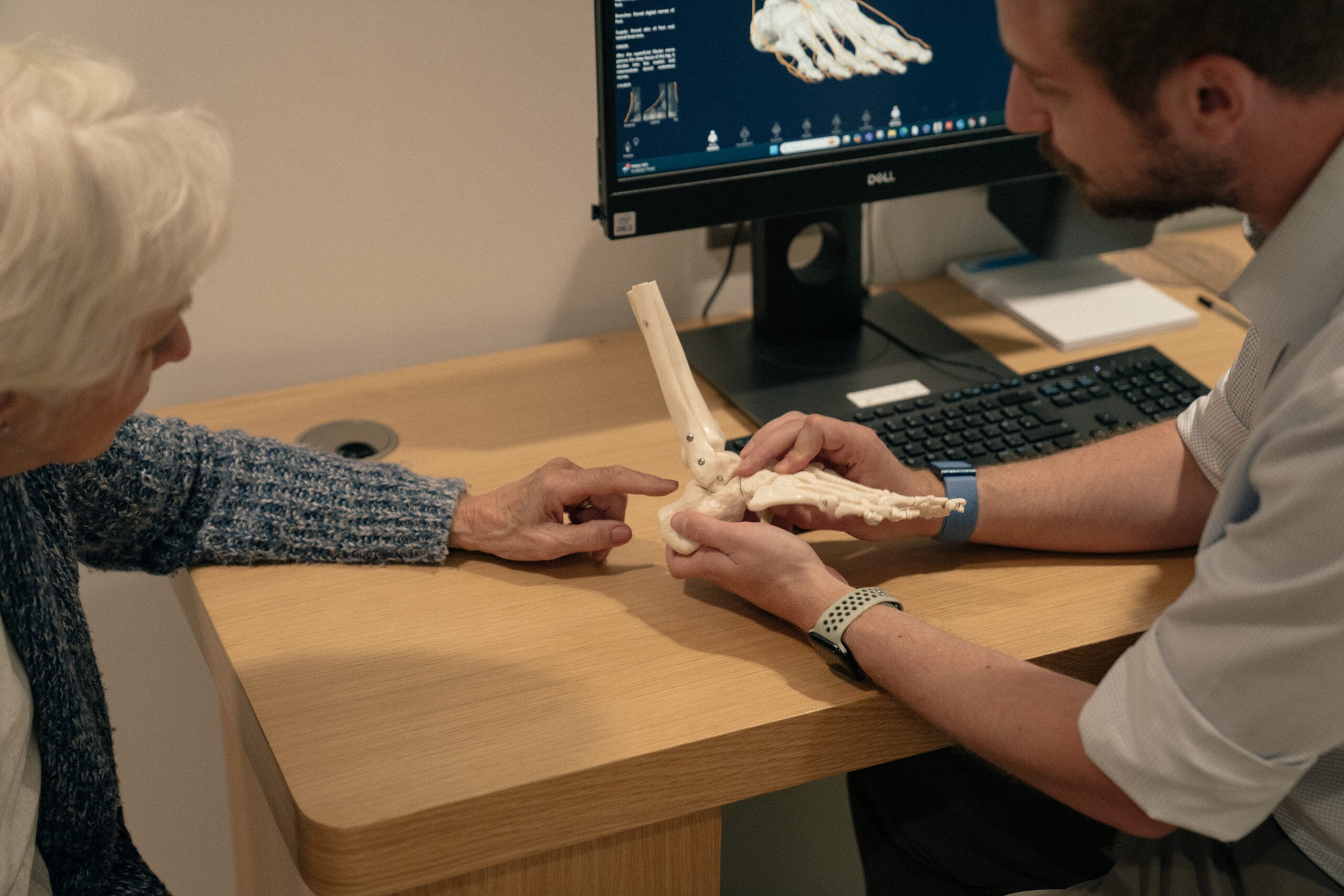 Patient pointing to medical model of foot with clinician