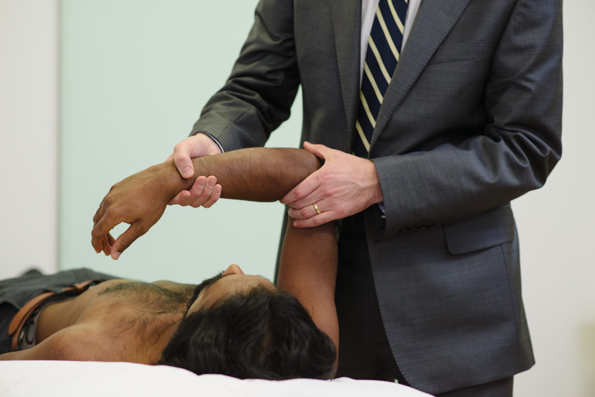 Clinician assessing patient arm's laying down