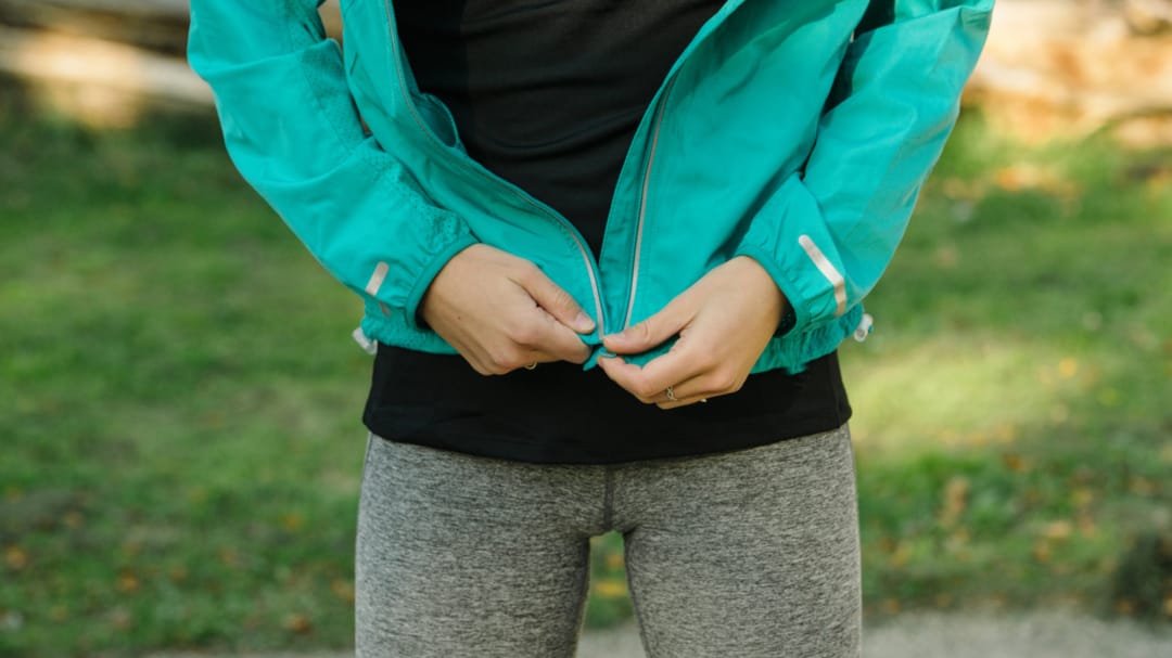 someone zipping up coat outside