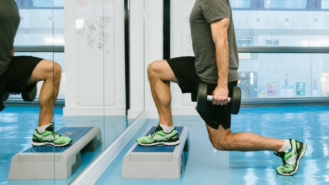 close up of a man lunging on a step with weights